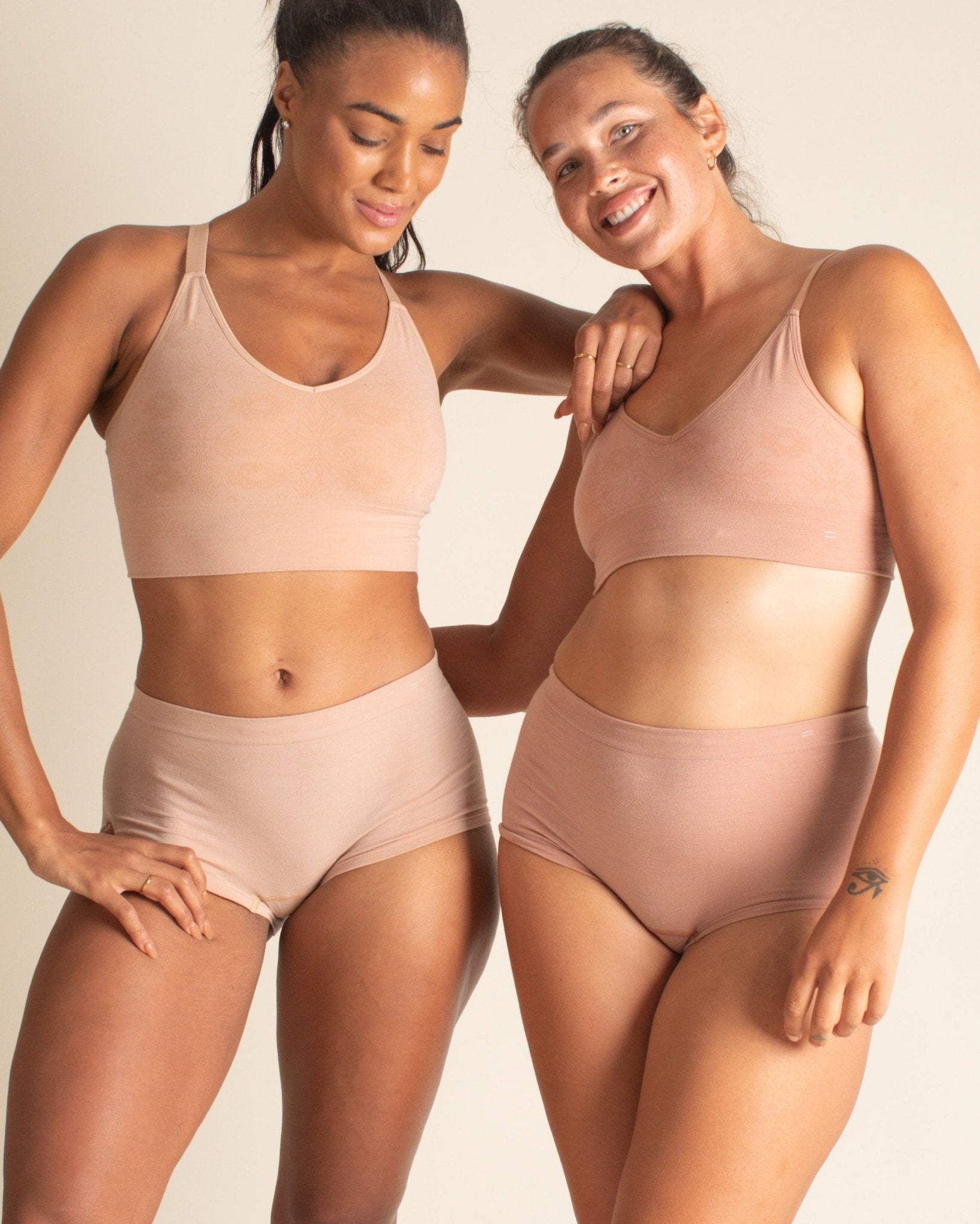 Two woman posing together in Merino underwear sets, wearing Merino boyshort underwear in shades of nude.