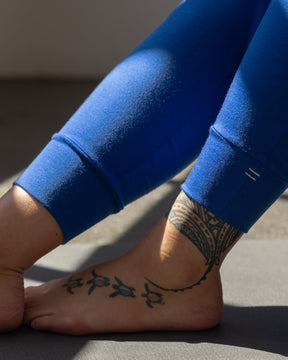 A close-up shot showing details of the Merino wool jogger ankle cuffs with a white equal sign embroidered resting on a gray yoga mat.