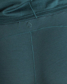 Close-up detail of teal BRANWYN Merino wool jogger sweatpants with embroidered heart logo. Made of 85% sustainable, regenerative Merino wool fibers.
