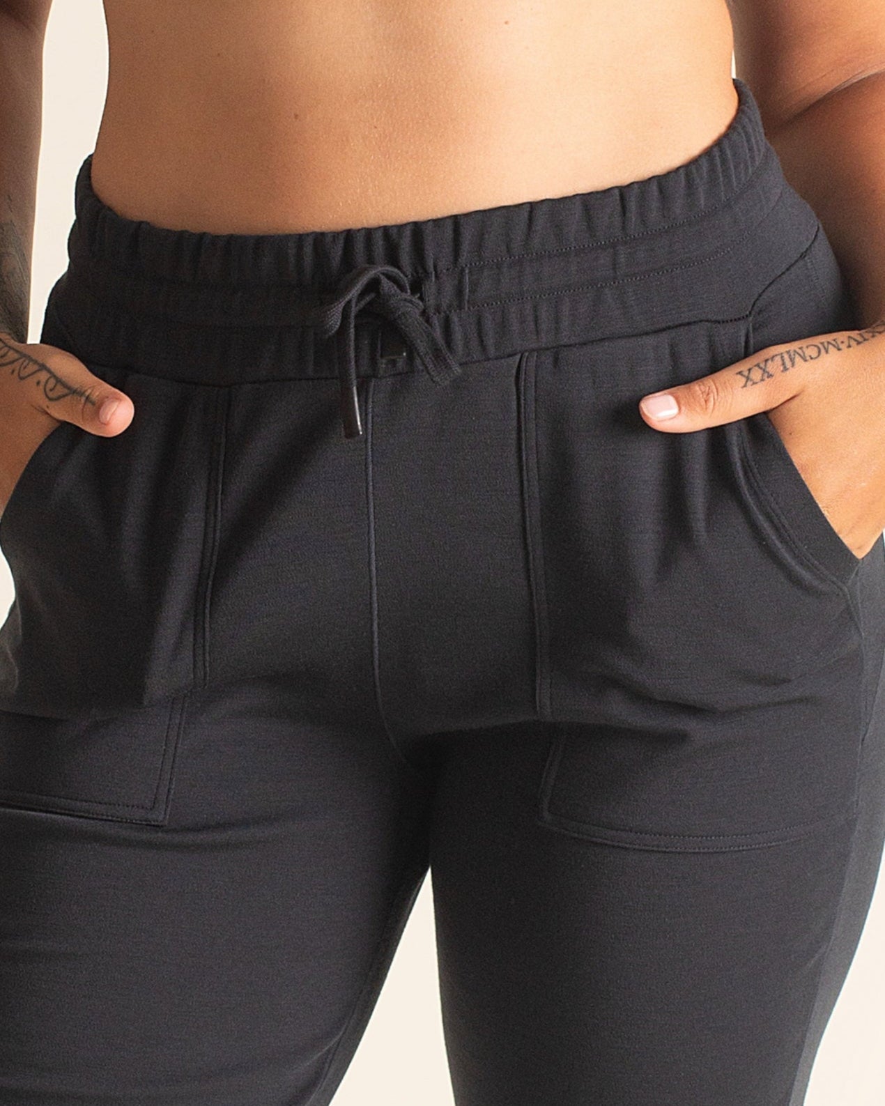 Detail of drawstring waistband and pockets of the BRANWYN women’s Merino joggers in black. Made of temperature-regulating, quick-drying, super soft Merino wool.