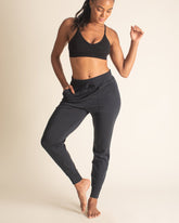 Woman stretching in black BRANWYN Merino wool jogger sweatpants. Sweat-wicking, quick-drying joggers perfect for yoga, the gym, walking, and running.