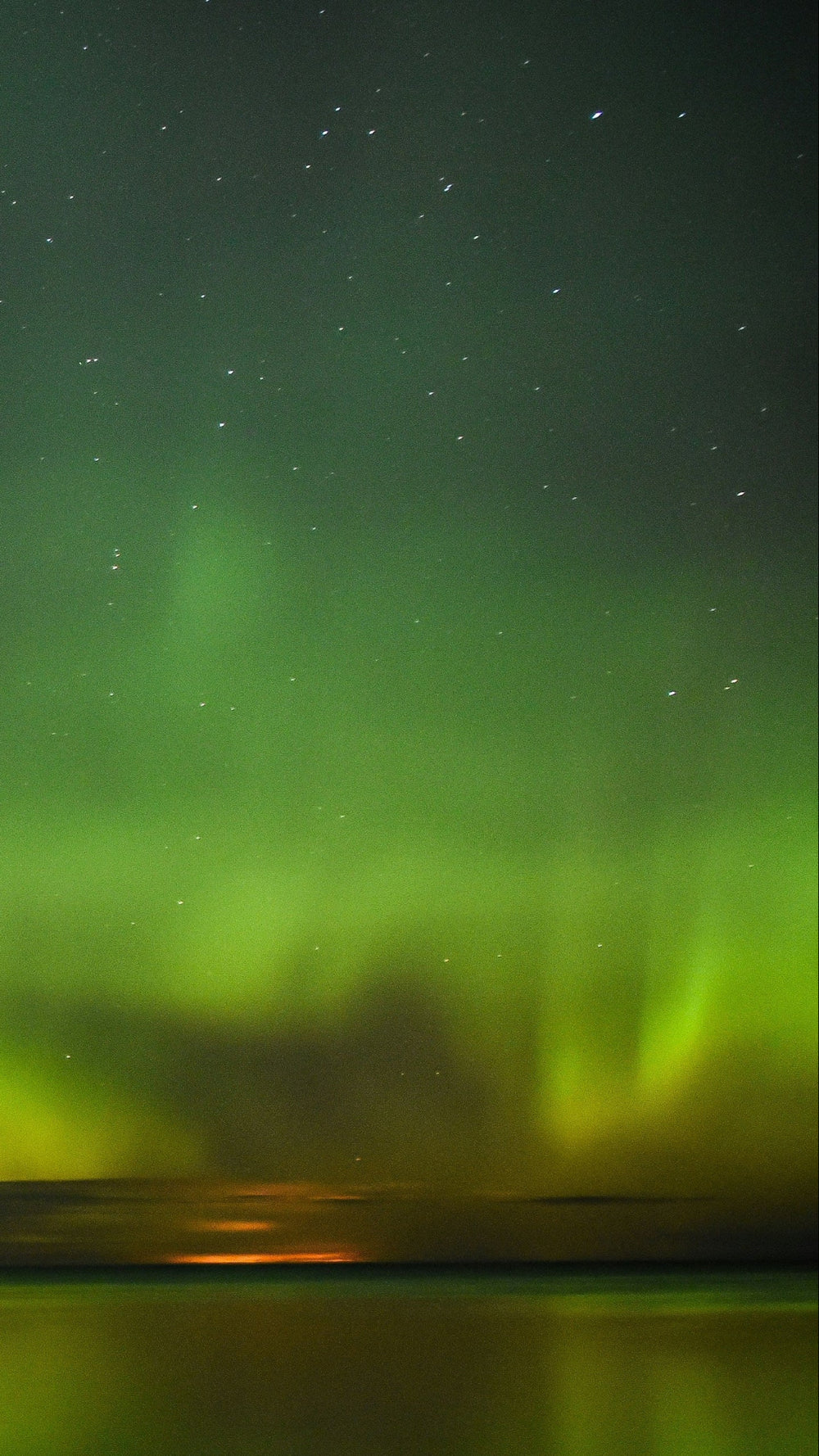 Aurora borealis over a lake with snowy landscape