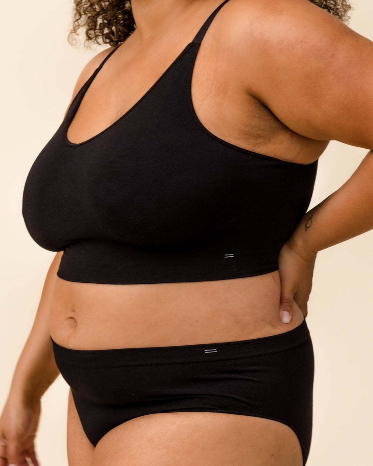 Woman wearing BRANWYN's black Essential Busty Bra, a bra from the Essential Collection. Made from soft, moisture-wicking Merino wool using seamless technology, this performance innerwear provides performance, comfort, and sustainability. The fabric is free from BPA, PFAS, and forever chemicals.